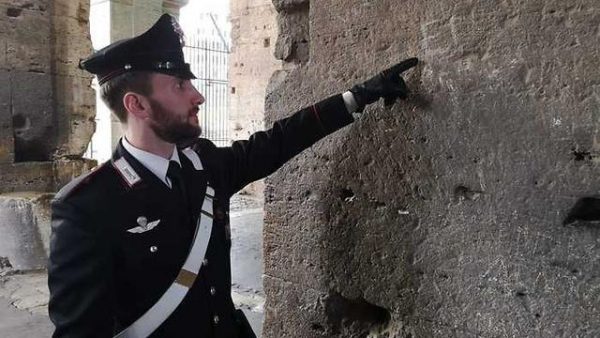 שוטר איטלקי בקולוסיאום, מצביע על החריטה. צילום: ANSA